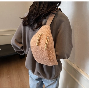 Detail of plush beige sherpa crossbody bag showing woven zipper pulls on a gray sweater