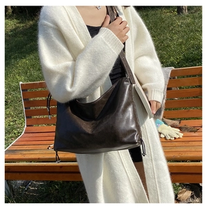 Detail of dark brown vintage faux leather tote bag with drawstrings during outdoor use