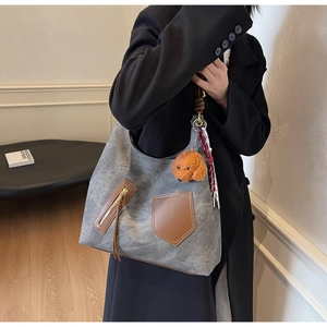 Detail of grey vintage tote bag with side pockets and cute puppy plush pendant