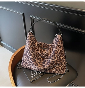 Close-up of leopard print tote bag featuring a black handle and metal chain strap