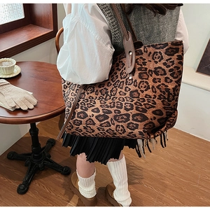 Close-up of leopard print tote bag with leather handles in a cozy cafe setting