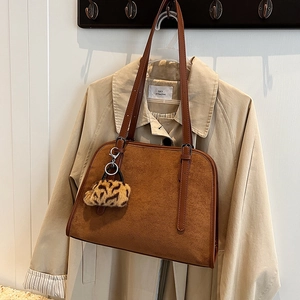 Vue détaillée du sac cabas en daim marron foncé avec un pompon à motif léopard