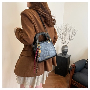 Close-up of black leather handbag with vintage texture, gold hardware and decorative charms