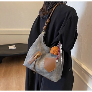 Detail of grey retro tote bag featuring brown leather straps and cute plush dog charm