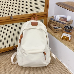 Detail of minimalist off-white canvas backpack with brown leather handles and zipper pulls