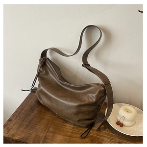 Detailed macro view of the brown matte leather hobo bag texture and woven strap knot
