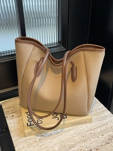 Chic beige lychee grain tote bag with brown straps on a marble surface and books