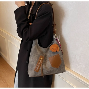 Detail view of large grey canvas tote bag with brown leather pockets and charms