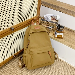 Detail view of ginger yellow nylon school backpack with leather logo and side pockets