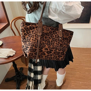 Close-up of leopard print tote bag with brown leather handles and metal rivet details