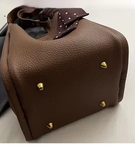 Macro detail of brown litchi grain leather bucket bag bottom with protective gold studs