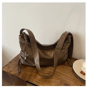 Detailed side view of brown hobo bag featuring drawstring knot and matte leather texture