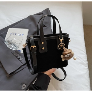 Détail du mini sac cabas noir avec charme monstre, rivets dorés et texture suède