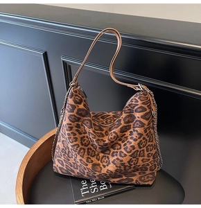 Detail of leopard print tote bag with brown leather strap and decorative metal chain