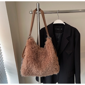 Detail of soft brown faux fur tote bag with brown leather straps hanging on a metal rack