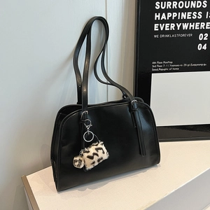 Détail du sac cabas noir avec un pendentif décoratif en peluche à motif léopard élégant