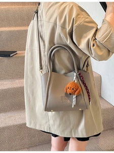 Sac seau gris en cuir grainé avec pendentif chien et pieds de protection dorés