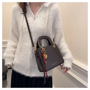 Detail of dark brown tote bag with gold hardware heart lock and polished texture