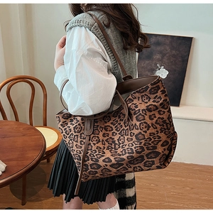 Macro shot of large leopard print tote bag with brown leather straps and detailed texture