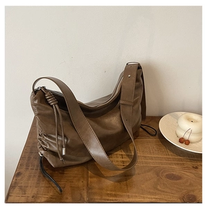 Detail view of brown leather hobo bag with drawstring sides on a rustic wooden table