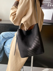 Chic black faux suede bucket bag for women with adjustable leather strap in a city setting