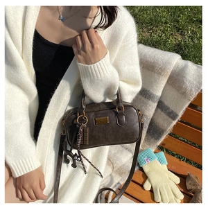 Detail of dark brown vintage PU leather pillow bag with gold logo and cat charm