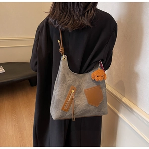 Detail of grey canvas tote with brown leather pockets and a cute bear keychain charm