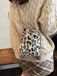 Faux fur leopard print bucket bag with drawstring closure worn on shoulder