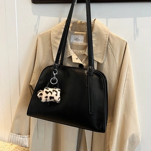 Détail d'un sac cabas noir minimaliste avec un pendentif peluche à motif léopard