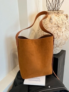 Caramel brown suede bucket bag with wide shoulder strap in a minimalist style