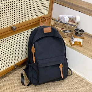Detail view of black nylon backpack with brown leather handles and adjustable side straps