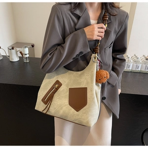 Beige canvas tote bag with brown leather trim and cute teddy bear charm on model