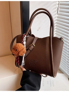 Sac seau en cuir marron avec pendentif chien et relief enjoy choc sur fond ensoleillé doux