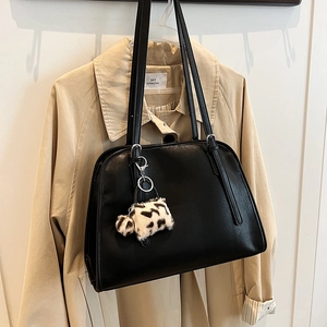 Détail d'un sac cabas en similicuir noir avec pompon léopard sur un trench