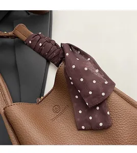 Detail of lychee pattern leather handbag with polka dot silk scarf and gold hardware
