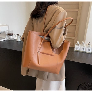 Brown leather tote bag featuring a practical back zipper pocket and slim shoulder straps