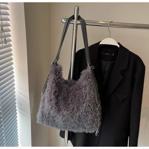 Detail of plush grey faux fur tote bag with dark leather strap and silver chain accent