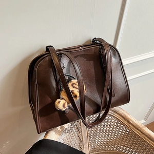 Détail d'un sac cabas en similicuir marron foncé avec un pendentif peluche léopard