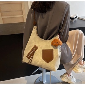 Detail of cream tote bag with brown contrast pockets and a cute puppy plush charm
