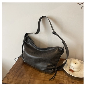 Close-up of distressed faux leather drawstring crossbody bag on a wooden table