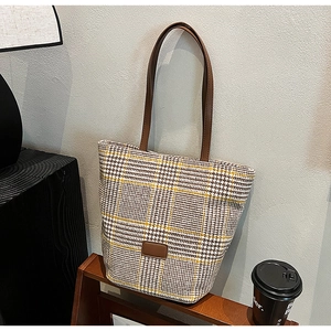 Dettaglio borsa shopper a quadretti giallo con etichetta in pelle e tracolla