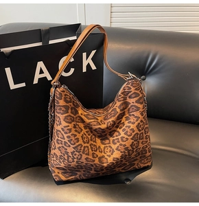 Detailed view of leopard print tote bag with silver chain and brown leather handles