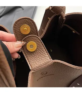 Detailed close-up of golden magnetic clasp on premium brown pebble leather handbag