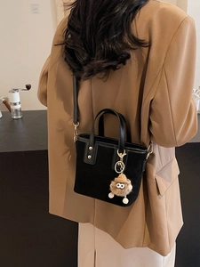 Sac cabas noir mat minimaliste avec breloque monstre et finitions en cuir