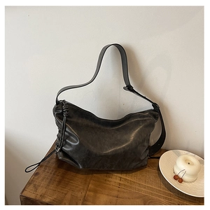Close-up of black hobo bag with vintage texture and knotted zipper detail