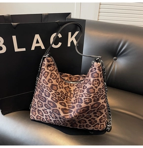 Close-up of leopard print tote featuring metal chain strap and zip closure detail
