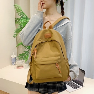 Ginger yellow nylon backpack featuring dark brown leather straps and front pocket detail