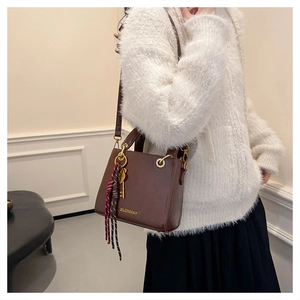 Close-up of brown leather handbag with gold logo, metal handle and stylish silk scarf