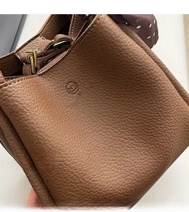Macro view of brown lychee grain leather bucket bag with gold hardware and polka dot scarf
