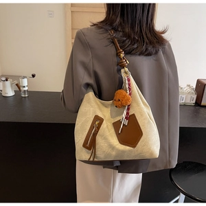 Detail of canvas tote bag with brown leather trim and cute puppy charm on model